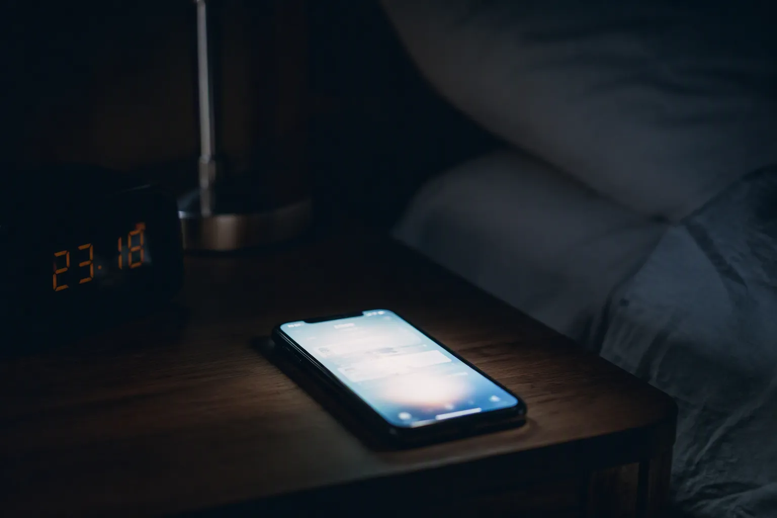 A phone lighting up on a bedside table in the dark